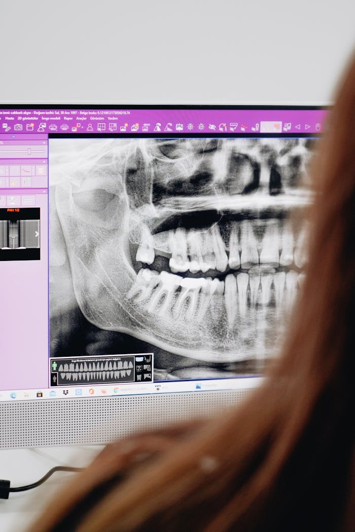 A close-up of a dentist reviewing a dental X-ray image on a computer screen, focusing on oral health analysis.